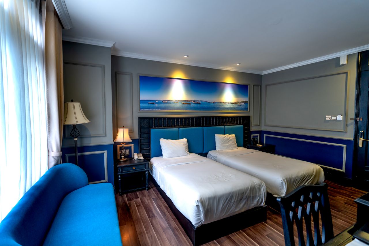Crafting Captivating Headlines: Your awesome post title goes here Stylish hotel room featuring blue decor, twin beds, and modern furnishings with ample natural light.
