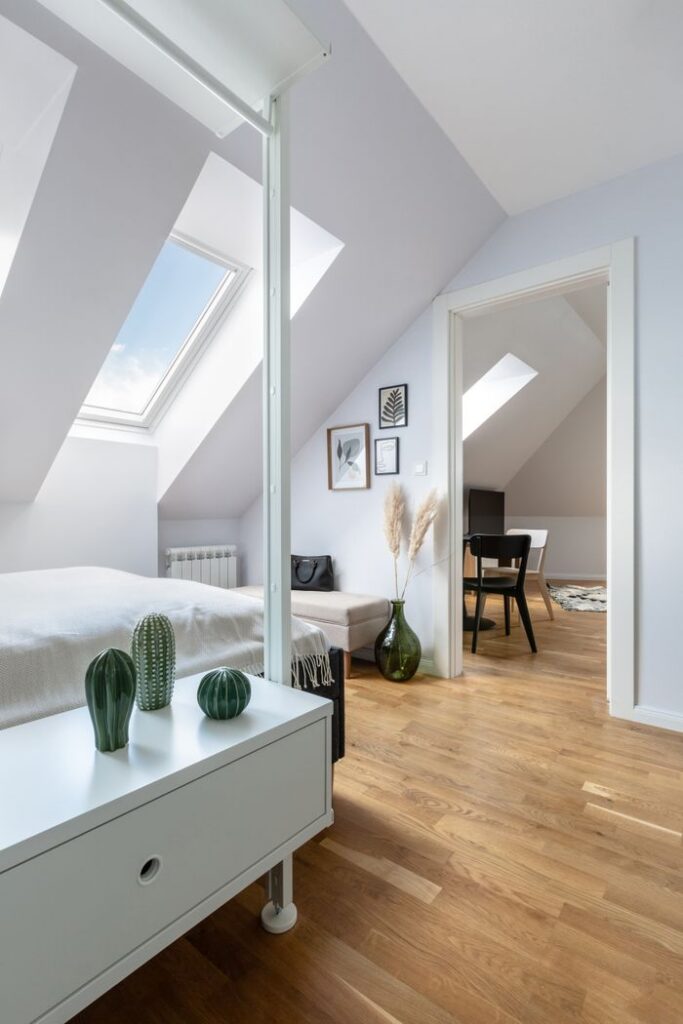 Bright, modern attic bedroom with skylight in Prague apartment, featuring minimalist decor.