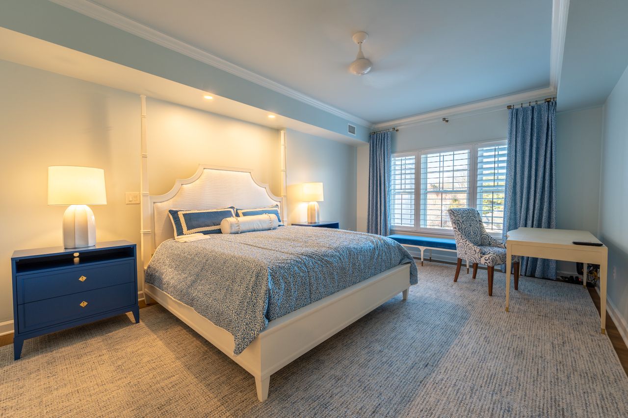 about-us-02 Luxurious bedroom with blue and white decor, featuring a king-size bed, elegant furniture, and soft lighting.